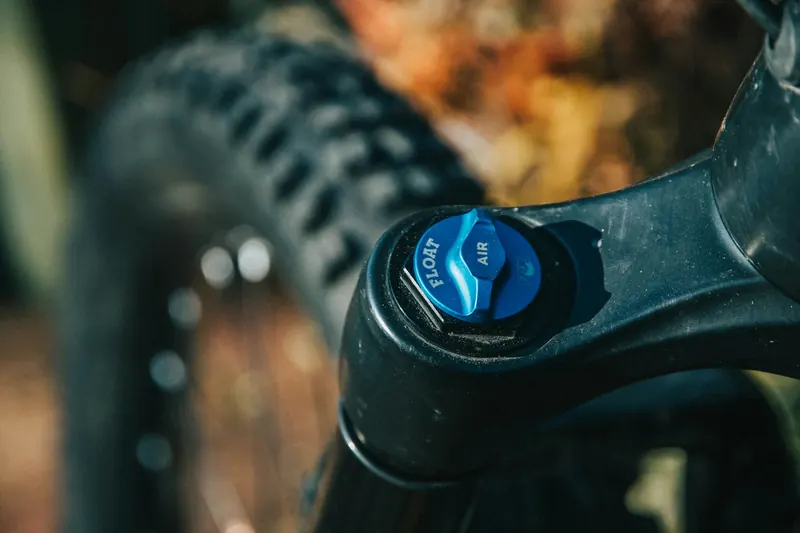 Nahaufnahme einer Federgabel mit blauer Luftkappe und Reifenprofil