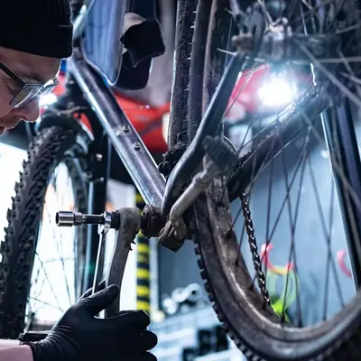Mechaniker mit Stirnlampe prüft ein E-Bike in der Werkstatt
