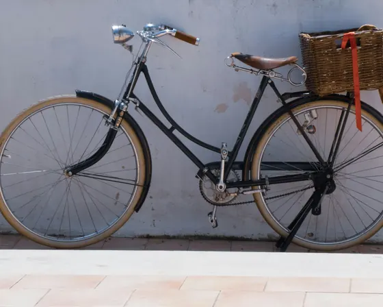 Klassisches Velo mit Ledersattel und Korb vor heller Wand