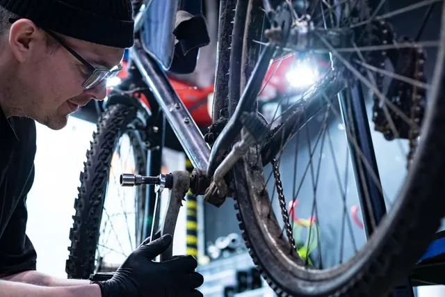 Velomechaniker bei der Arbeit an einem Velo in einer abgedunkelten Werkstatt