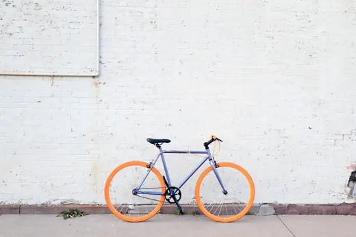 City-Velo mit orangen Felgen vor einer weissen Wand