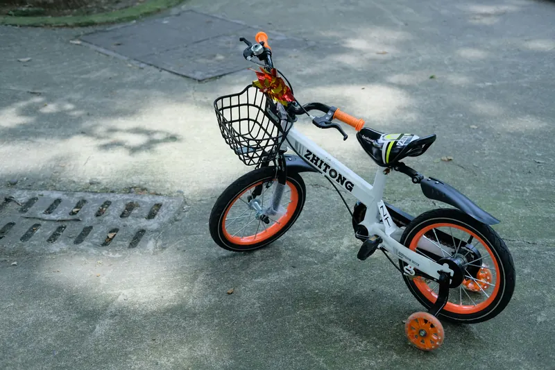 Kindervelo mit Stützrädern auf grauem Asphalt