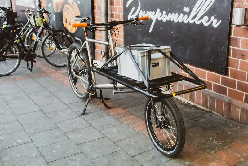 Longtail-Cargovelo mit verlängertem Hinterbau und langem Gepäckträger vor einer Backsteinwand