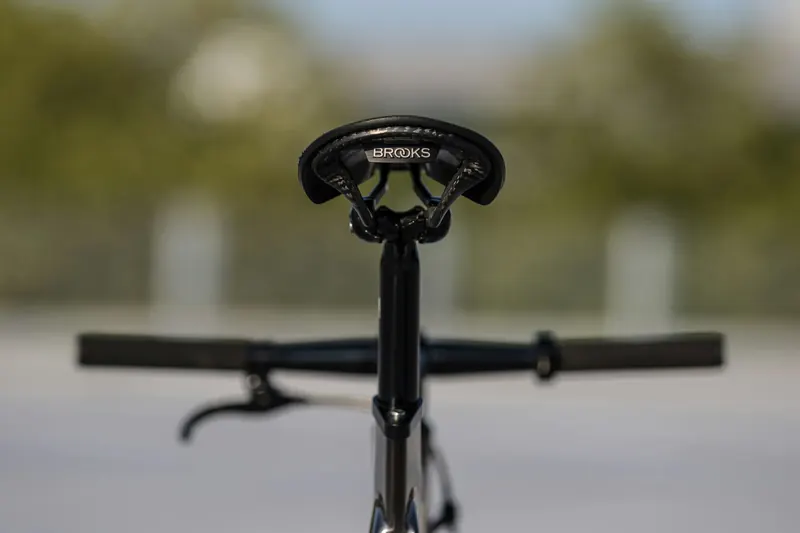 Schwarzes Velo mit Rennlenker und Carbon-Laufrädern vor dunklem Hintergrund
