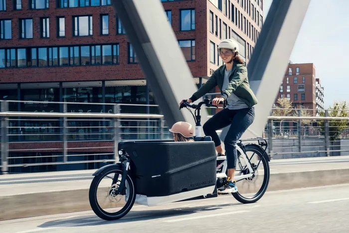 Mutter mit Kind im Riese & Müller Packster2 70 auf einer Brücke in der Stadt