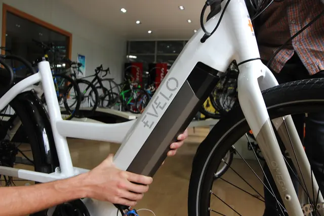 Weisses E-Bike im Verkaufsraum, ein Akku wird ins Unterrohr geschoben