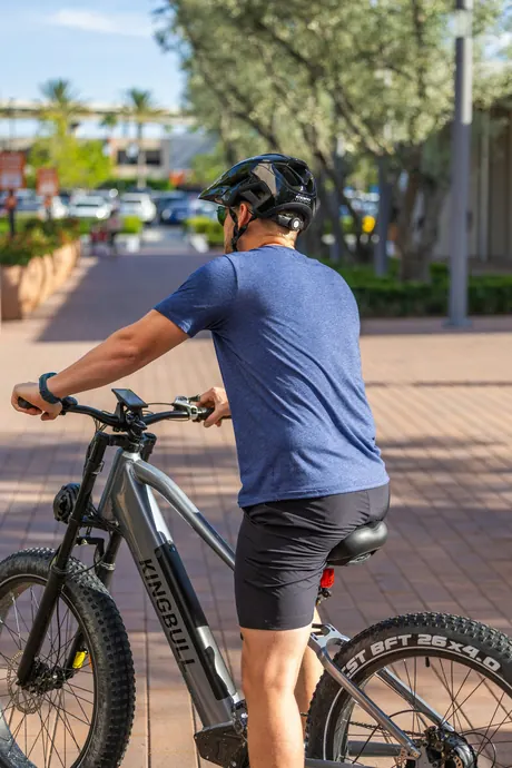 Fahrer mit Helm auf einem E-Mountainbike in der Stadt, Hochformat