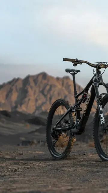 Schwarzes E-Mountainbike von Ramsauer Radsport auf Schotter vor Bergkulisse